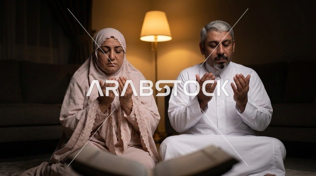 زوجان سعوديان مسنان يؤديان الدعاء في المنزل