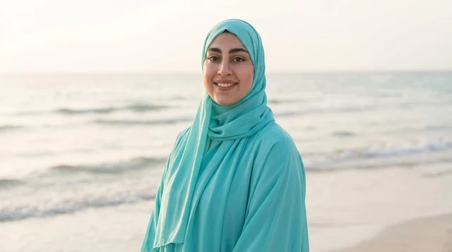 امرأة عربية بعباءة فيروزية على شاطئ البحر