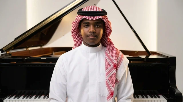 رجل سعودي بالزي التقليدي أمام بيانو أسود رجل سعودي بالزي التقليدي أمام بيانو أسود