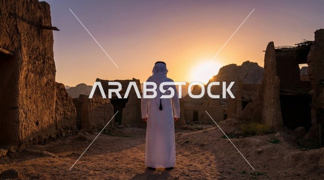 رجل سعودي بين الأطلال الطينية وقت غروب الشمس