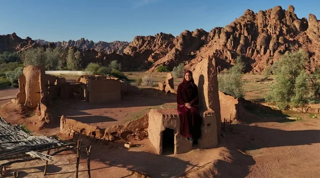 امرأة سعودية باللباس التقليدي في الأطلال الطينية القديمة