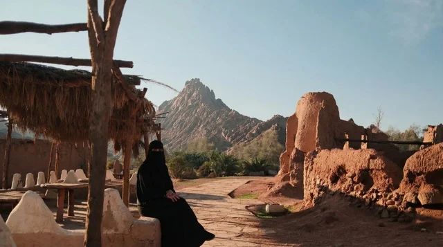امرأة سعودية بالعباءة التقليدية في موقع تراثي