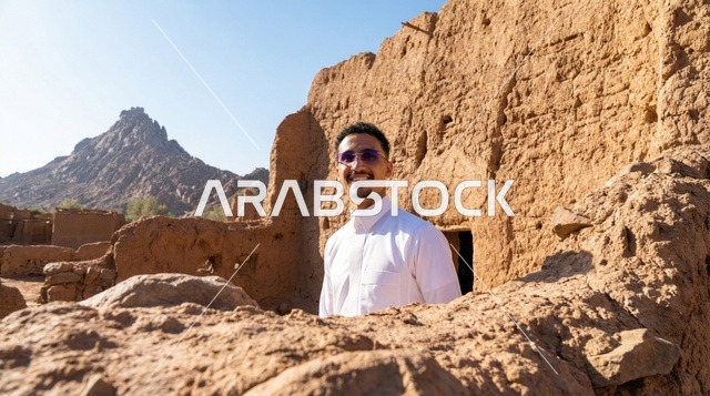 رجل سعودي بالثوب الأبيض داخل بيت طيني تراثي