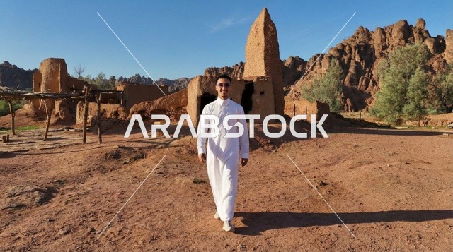 رجل سعودي بالثوب الأبيض يمشي في قرية تراثية