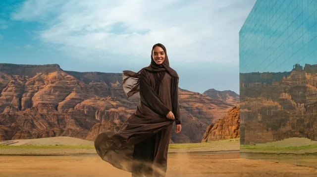امرأة سعودية بالعباءة أمام مبنى مرايا في العلا