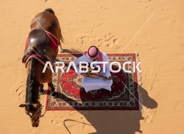 رجل سعودي يعزف العود في الصحراء مع الخيل