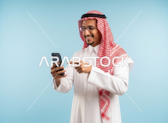 رجل سعودي بالثوب يشير إلى شاشة الهاتف الذكي