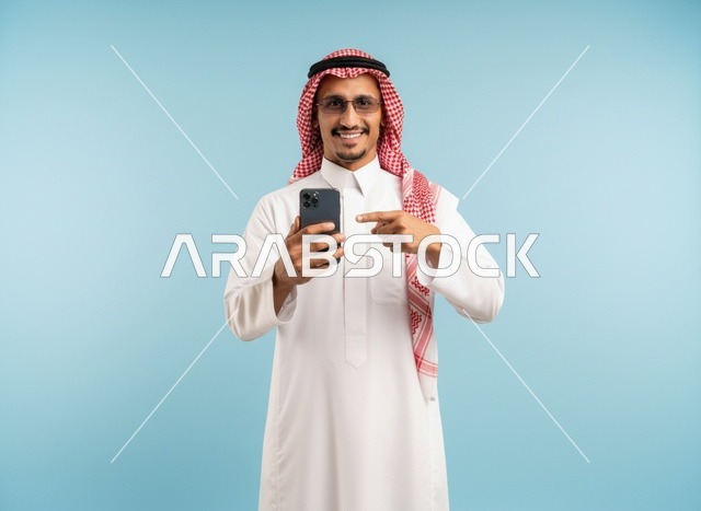 رجل سعودي يشير إلى هاتف ذكي بخلفية زرقاء