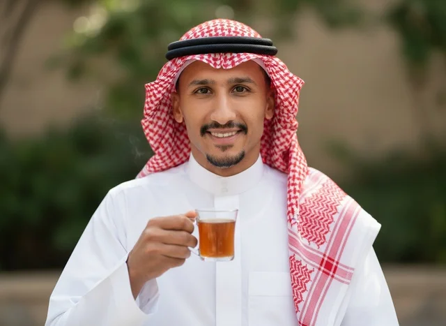 رجل سعودي بالزي التقليدي يحمل كوب شاي