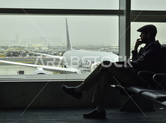 صورة لمسافر عربي خليجي ينتظر رحلته في قاعة الانتظار في مطار حمد الدولي بمدينة الدوحة، رحلة سياحية ،  رحلة عمل ،سياحة وسفر ، معالم دولة قطر