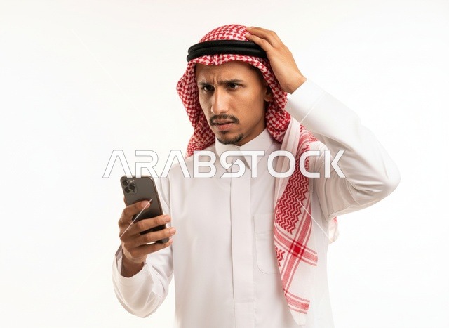 رجل سعودي مرتبك يستخدم الهاتف الذكي بخلفية بيضاء