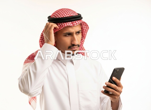 رجل سعودي محتار ينظر إلى الجوال