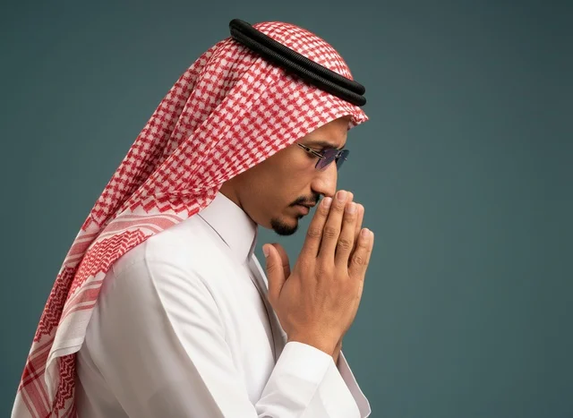رجل سعودي يرتدي الثوب التقليدي في وضعية الدعاء