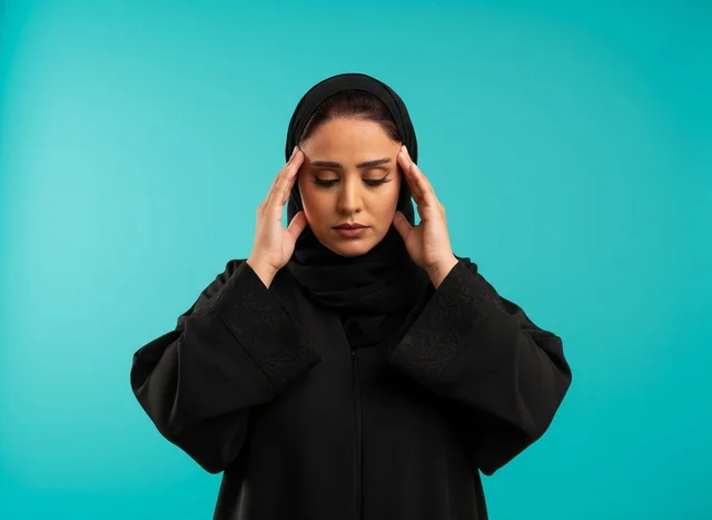 امرأة عربية بالعباءة تعاني من الصداع والتوتر