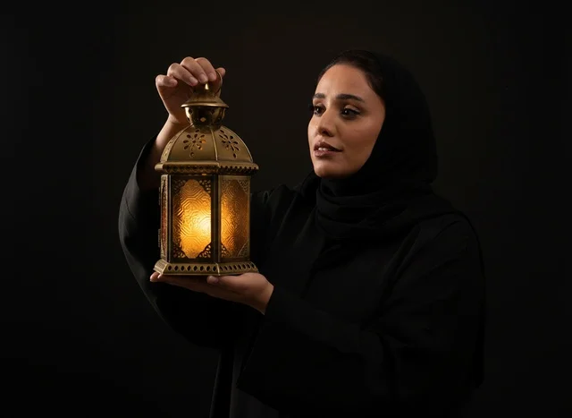 امرأة عربية بالعباءة تحمل فانوس رمضان المضيء