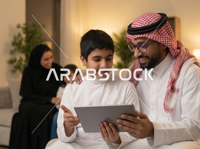 أب سعودي وابنه يستخدمان الجهاز اللوحي في المنزل