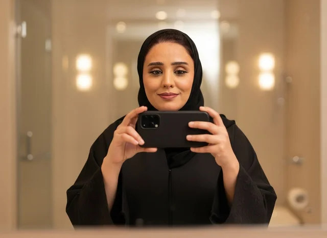امرأة سعودية بالعباءة تلتقط سيلفي أمام المرآة