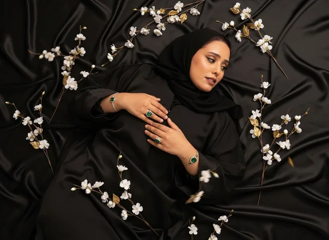 امرأة سعودية بالعباءة ومجوهرات الزمرد على الحرير