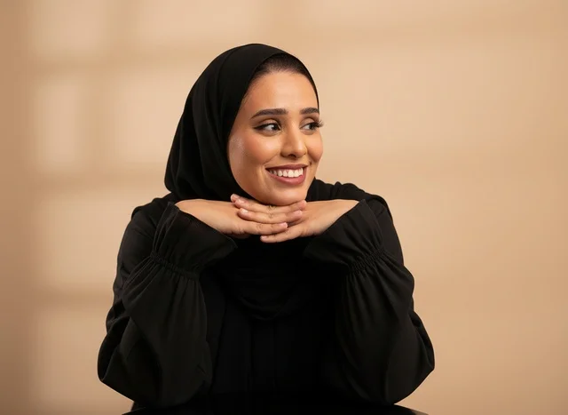 امرأة سعودية مبتسمة ترتدي الحجاب والعباءة السوداء