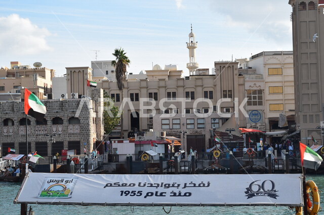 صورة مقربة للافتة معلقة على قارب خشبي في المدينة القديمة بدبي في الإمارات العربية المتحدة، قارب نقل خشبي، علم دولة الإمارات، معالم الإمارات، ساحة لسوق شعبي في دبي، السياحة في الإمارات