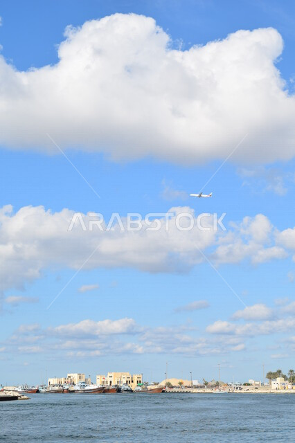 طائرة من طيران الإمارات تحلق في سماء مدينة دبي بالإمارات العربية المتحدة، مطار دبي الدولي، وسائل المواصلات الجوية، رحلات جوية سياحية، الطيران الإماراتي، شركة الطيران الوطنية الإماراتية، السياحة في الإمارات