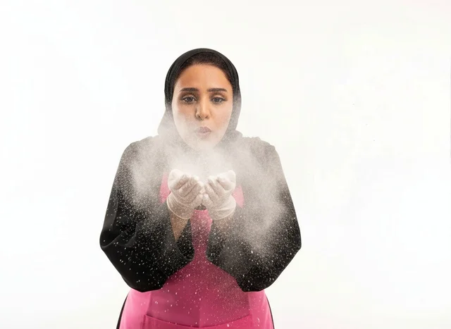 طباخة سعودية تنفخ الطحين بخلفية بيضاء