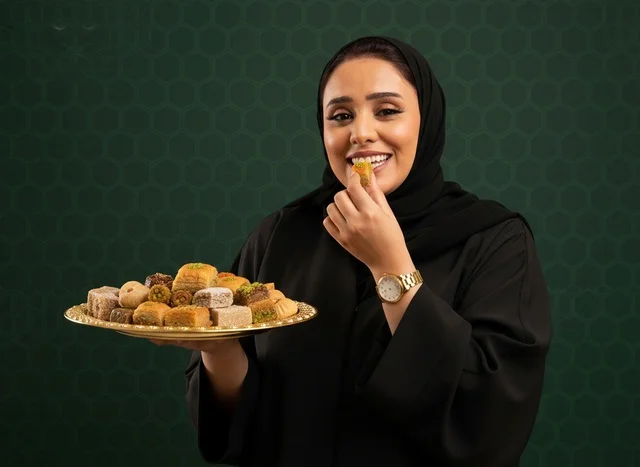 Saudi Woman in Abaya with Traditional Arabic Sweets