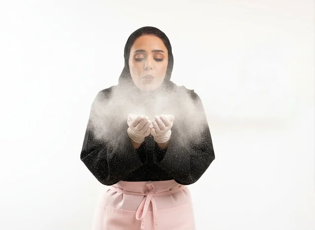 Saudi Female Chef Blowing White Flour on White Background