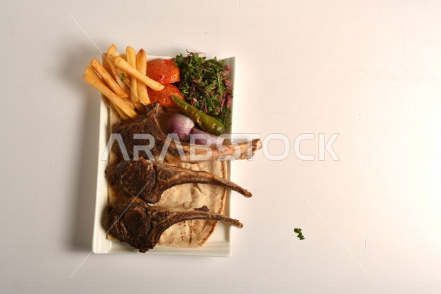 صورة مقربة لطبق يحتوي على ريش اللحم مع الخضروات مصورة على خلفية بيضاء، اللحم المشوي اللذيذ، لحوم الضأن، مطعم المشاوي، البطاطس والفلفل المشوي، اكلات عربية شرقية، وجبات الطعام السريعة، المطاعم العربية