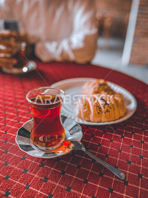 صورة مقربة لقطعة من الكوروسون مع كوب من الشاي، مشروبات ساخنة، مخبوزات لذيذة، فطور عربي، كافيهات ومطاعم عربية