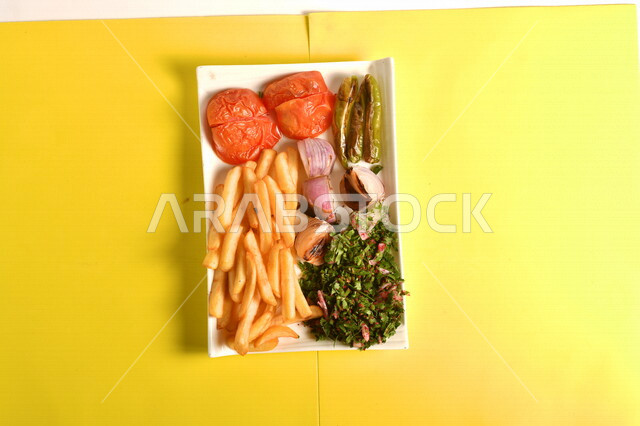 Close-up of a plate of grilled vegetables with potatoes on a yellow background, cut onions, tomatoes and delicious grilled peppers, grill restaurant, oriental Arabic cuisine, delicious meals, Arabic restaurants