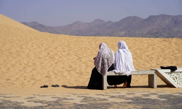 نساء عربيات باللباس التقليدي يجلسن في الصحراء