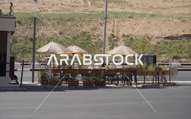 Outdoor Roadside Cafe Seating with Umbrellas and Desert Hill