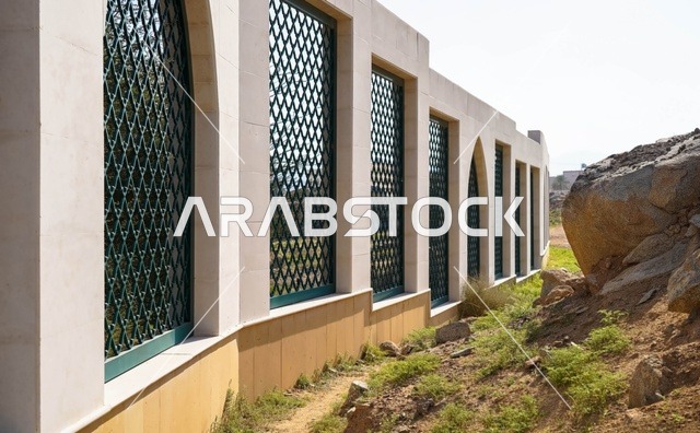 جدار حجري حديث بتصميم مشربية مع شبكة معدنية خضراء