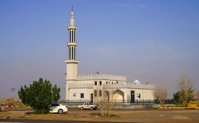 مسجد محلي في السعودية مع مئذنة بيضاء مرتفعة في النهار