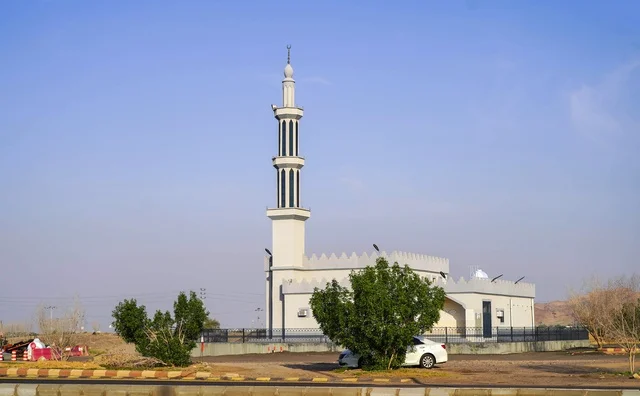 تصميم مسجد حديث بمئذنة بيضاء تحت السماء الزرقاء