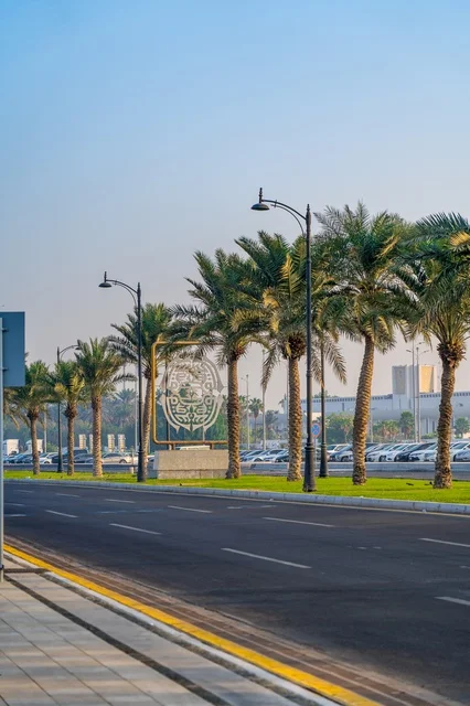 Saudi National Emblem Monument on Roadside with Palm Trees
