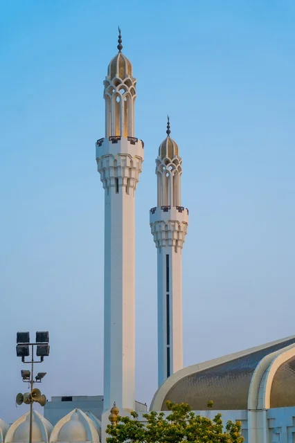 Two Modern White Mosque Minarets Against Clear Blue Sky