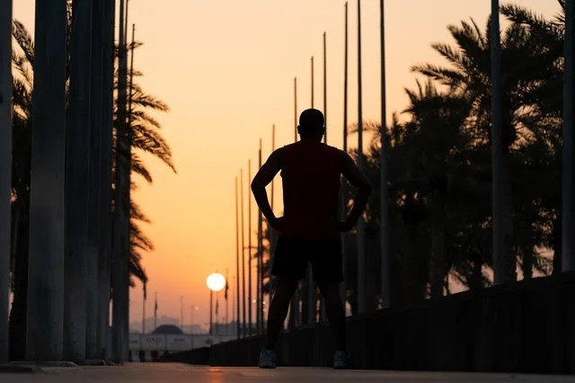 خيال عداء رياضي عند غروب الشمس بين أشجار النخيل