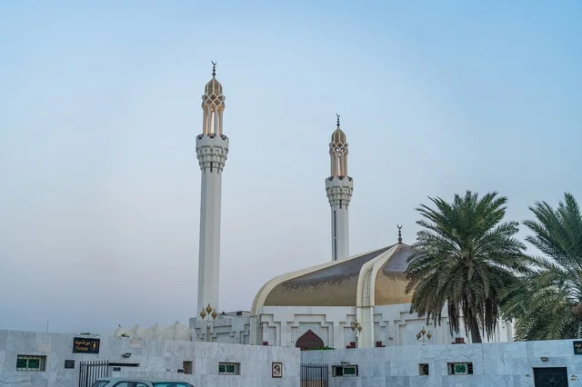 مسجد حديث بقبة ذهبية ومآذن بيضاء تحت السماء الزرقاء