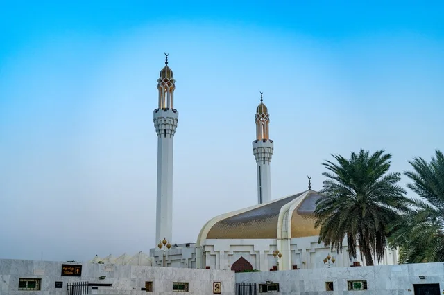 مسجد حديث بقبة ذهبية ومآذن بيضاء تحت السماء الزرقاء