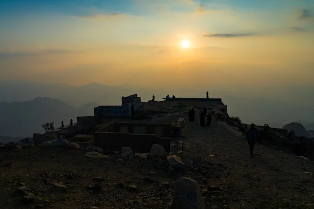 Silhouettes of People on Mountain Peak During Sunset