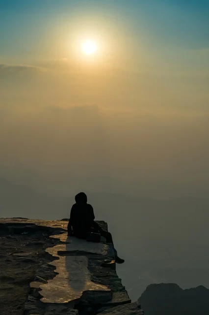 Silhouette of a Person on Mountain Cliff at Sunrise