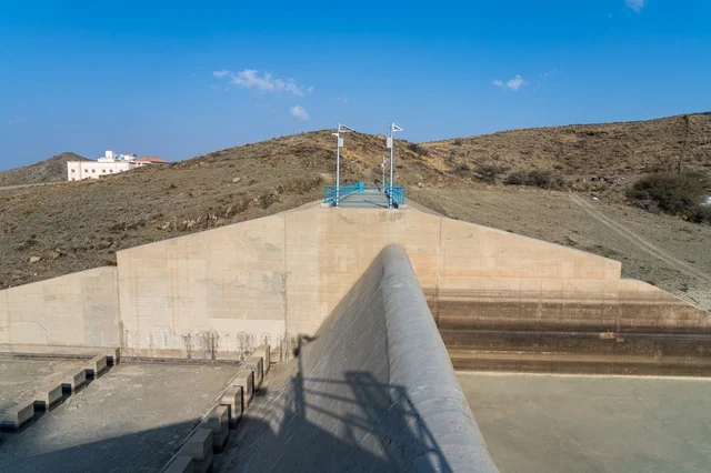 Concrete Dam Structure in Arid Hills Under Blue Sky