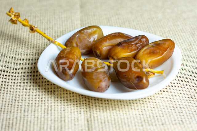 A close-up of a plate of healthy dates, Deglat Nour dates, a meal with a high nutritional value, Ramadan hospitality, types of healthy and delicious dates