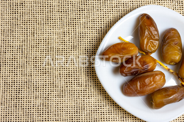A close-up of a plate of healthy dates, Deglat Nour dates, a meal with a high nutritional value, Ramadan hospitality, types of healthy and delicious dates