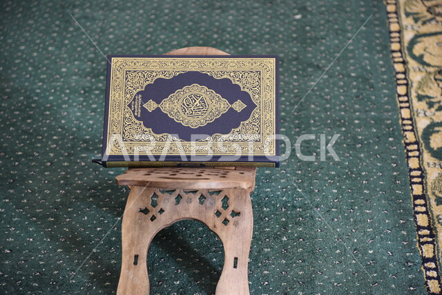 المصحف الشريف على حامل خشبي في المسجد، الصلاه والدعاء في المسجد، العبادة والتقرب الى الله، قراءة وتلاوة القران، التعبد في بيوت الله، ذكر الله، تحفيظ القران الكريم، تفسير القرآن