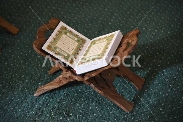 المصحف الشريف على حامل خشبي في المسجد، الصلاه والدعاء في المسجد، العبادة والتقرب الى الله، قراءة وتلاوة القران، التعبد في بيوت الله، ذكر الله، تحفيظ القران الكريم، تفسير القرآن