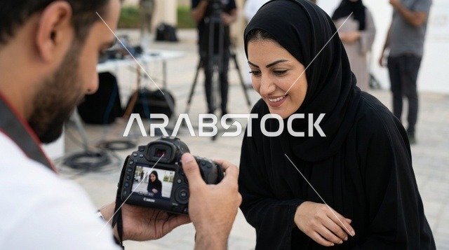 مصور يعرض لقطة الكاميرا على امرأة عربية بالعباءة