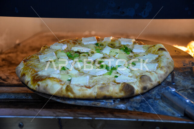 صورة مقربة لفطيرة البيتزا اثناء خروجها من الفرن، البيتزا والفطائر الشهية، اكلات عربية شرقية، وجبات الطعام الشهية، المطاعم العربية، وجبات صحية